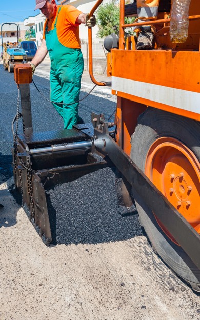 Road worker handling asphalt